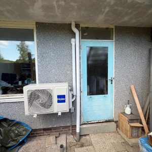 Blauwe deur met airconditioner en bouwmaterialen buiten.