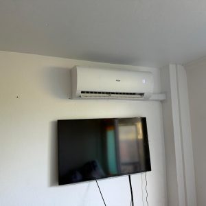 Airconditioner en tv aan witte muur.