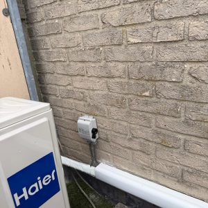 Airconditioningunit gemonteerd op bakstenen muur